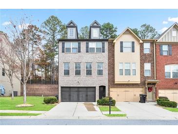Well-manicured townhome showcasing a welcoming two-car garage and detailed architectural design at 3229 Hallmark Ln, Buford, GA 30519