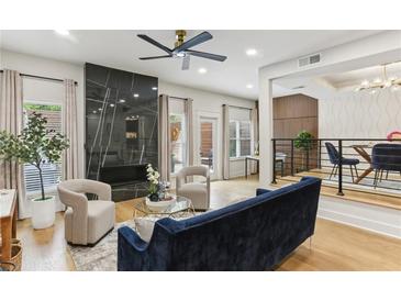 Bright living room with a fireplace, modern ceiling fan, and beautiful hardwood flooring at 1906 Variations Ne Dr, Atlanta, GA 30329