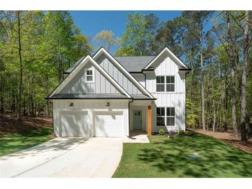 Charming two-story home with white siding, gray accents, attached two-car garage, and a well manicured lawn at 5086 Cumberland Ct, Villa Rica, GA 30180
