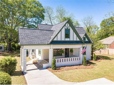 Charming two-story home with a landscaped yard, covered porch, and beautifully painted in cream and green at 181 W Hightower Trl, Social Circle, GA 30025