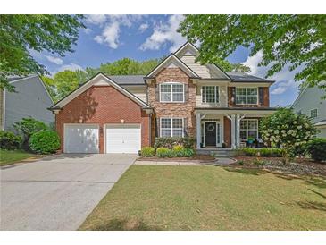 Charming two-story home with brick and stone accents, a manicured lawn, and a two-car garage at 3870 Cabalzar St, Cumming, GA 30040