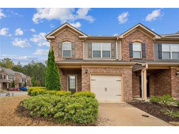Brick townhome with an attached one car garage and manicured landscaping at 7779 Haynes Park Cir, Lithonia, GA 30038