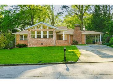 Charming brick home with a well-manicured lawn, a driveway with a carport, and mature trees providing ample shade at 698 N Superior Ave, Decatur, GA 30033