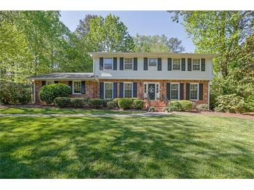 Charming two-story home with a brick facade, black shutters, and a well-manicured front lawn at 1569 Chateau Dr, Dunwoody, GA 30338