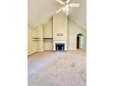 Living room featuring a fireplace, vaulted ceilings, carpeted floors, and built-in shelving at 25 Derby Dr, Hiram, GA 30141