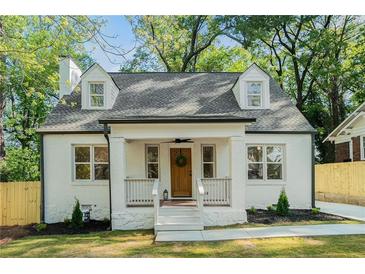 Charming home with a white brick exterior, dormer windows, wood door and welcoming front porch at 1555 Olympian Sw Way, Atlanta, GA 30310