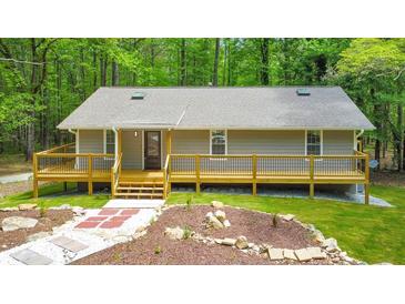 Charming home featuring a welcoming front porch and landscaped front yard in a serene setting surrounded by trees at 2633 Jonesboro Rd, Fairburn, GA 30213