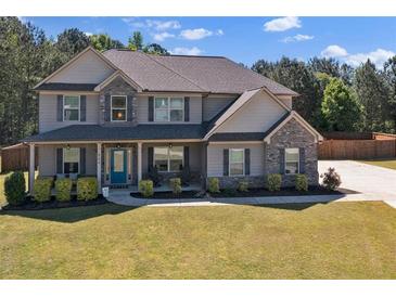 Two-story home featuring a manicured lawn, gray siding, stone accents, and a welcoming covered front porch at 524 Trousseau Ln, Mcdonough, GA 30252