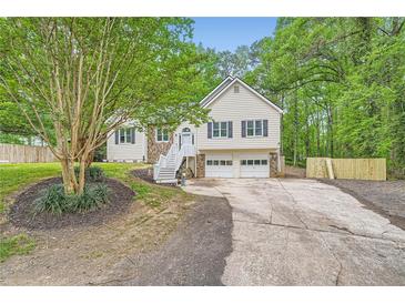 Charming home with a two-car garage, a well-maintained lawn, and beautiful, mature trees at 5640 Rolling Oaks Dr, Cumming, GA 30040