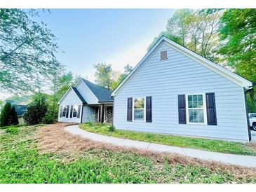 Charming single-story home featuring light blue siding, dark shutters, and a well-manicured lawn at 7675 Lanier View Rdg, Cumming, GA 30041