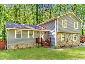 Charming two-story home featuring stone accents and gray siding nestled among lush greenery and a well-manicured lawn at 484 Aberdeen Dr, Stonecrest, GA 30083