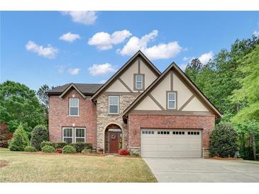 Charming two-story brick home with stone accents and a well-manicured lawn under a sunny sky at 3215 Trowbridge Dr, Cumming, GA 30040