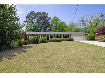 Charming brick ranch home with manicured lawn, a front porch, an attached two-car garage and mature trees at 4350 Bonaparte Dr, Tucker, GA 30084