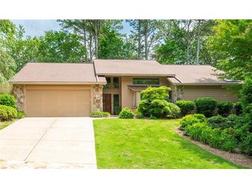 Charming single-Gathering home featuring an attached garage, lush landscaping, and stone accents at 4030 Muirfield Ln, Marietta, GA 30068