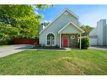 Charming home featuring a red door, arched window, and well-manicured lawn at 30 Village Dr, Cartersville, GA 30121