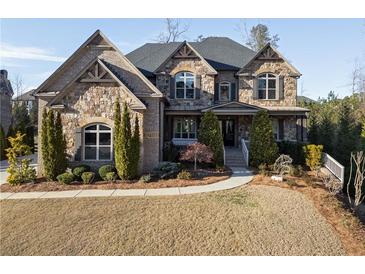 Beautiful stone home features a manicured lawn and mature evergreens highlighting the architectural details at 12640 Hearthstone Way, Alpharetta, GA 30009