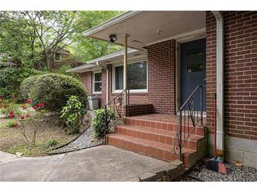 Brick home entrance featuring tiled steps, black railing, and a tidy front yard landscape with budding red flowers at 2383 N Decatur Rd, Decatur, GA 30033