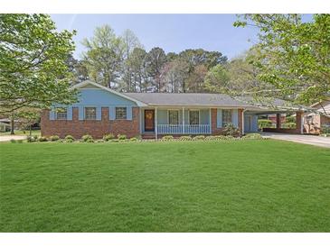 Charming single-story brick home with a well-manicured lawn and covered parking area at 699 Rollingwood Dr, Stone Mountain, GA 30087