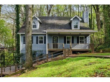 Charming two-story home featuring a cozy front porch, classic black shutters, and a well-maintained yard surrounded by lush trees at 4716 Alpine Sw Dr, Lilburn, GA 30047