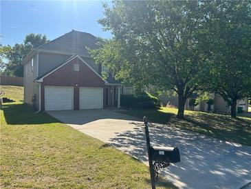 Charming two-story home boasts a two-car garage, and a well-manicured front yard at 3334 Rockmill Dr, Ellenwood, GA 30294