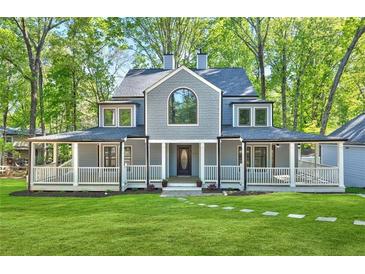 Charming two-story home with inviting front porch and well-manicured lawn surrounded by lush trees at 100 Little Ridge Rd, Berkeley Lake, GA 30096