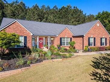 Charming one-story brick home with a landscaped front yard, complete with a red door and black shutters at 522 Plantation Creek Dr, Loganville, GA 30052