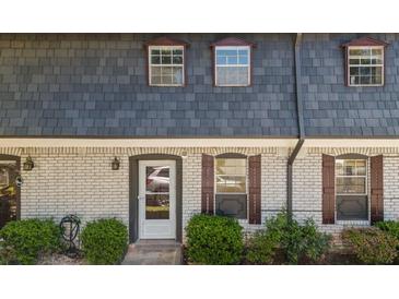 Charming townhouse featuring a brick facade, gray roofing, and well-maintained front yard landscaping at 305 Stonecliff Ct, Stone Mountain, GA 30083