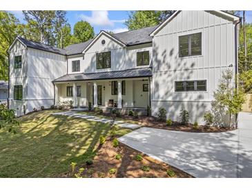 Stunning two-story home featuring a black roof, black framed windows, white siding and a covered front porch at 4785 Longchamps Dr, Sandy Springs, GA 30319