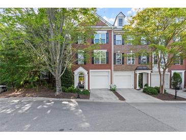 Charming brick townhome featuring a two-car garage, neat landscaping, and classic architectural details at 4912 Waters Edge Trl, Roswell, GA 30075