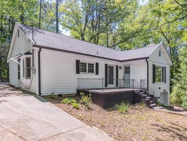 Charming home with white siding, a dark roof, and updated windows, on a wooded lot with driveway at 5201 Skyline Dr, Stone Mountain, GA 30083