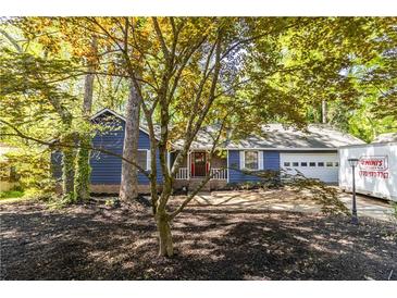 Charming blue home featuring a well-manicured front yard and an attached garage at 5272 Cumberland Way, Stone Mountain, GA 30087
