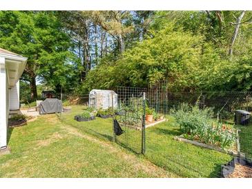 Spacious backyard featuring a lush garden, greenhouse, and secure fencing for outdoor enjoyment at 2014 Anchor Way, Buford, GA 30518