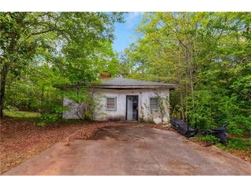 Exterior shot of a small, rundown single-story house with a visible yard needing maintenance at 3090 Sunset Se Rd, Conyers, GA 30094