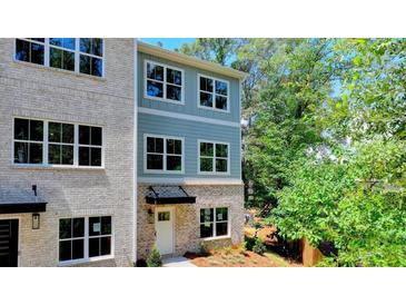 Charming exterior with brick and blue siding, large windows, and well-maintained landscaping at 5443 Blossomwood Sw Trl, Mableton, GA 30126
