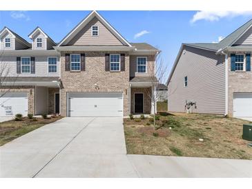 Charming two-story brick townhome featuring an attached garage and manicured front lawn at 2851 Fareed St, Douglasville, GA 30135
