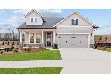 Charming home featuring a two-car garage, well-kept lawn and traditional architectural details at 214 Strawberry Ln, Woodstock, GA 30189