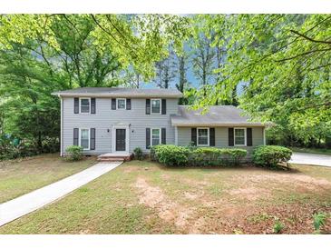 Traditional home with a manicured lawn, dark shutters, and a walkway leading to the front door at 4261 Autumn Hill Dr, Stone Mountain, GA 30083