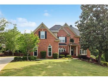 Stately brick home with manicured lawn and mature trees, showcasing classic architectural details and inviting curb appeal at 470 W Magnolia Cir, Johns Creek, GA 30005