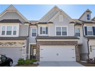 Charming townhome with a two-car garage and landscaped front yard with brick and grey shingle facade at 2946 Stockholm Way, Suwanee, GA 30024