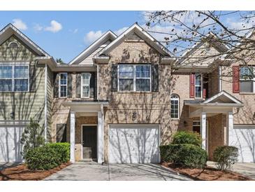 Charming brick townhome featuring an attached garage, front yard landscaping, and inviting front entrance at 2872 Cross Creek Ct, Cumming, GA 30040