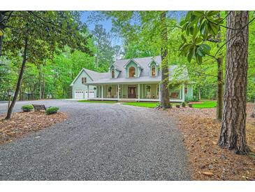 Charming home with a full front porch, rocking chairs and swing, set amongst mature trees at 2010 Univeter Rd, Canton, GA 30115