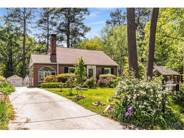 Charming brick home with a well-manicured lawn, flowering shrubs, and a classic brick chimney at 1919 Edinburgh Ne Ter, Atlanta, GA 30307