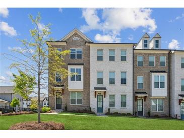 Charming townhome exterior with brick and white facade, complemented by a lush green lawn and tree at 3130 Bennett Creek Ln, Suwanee, GA 30024
