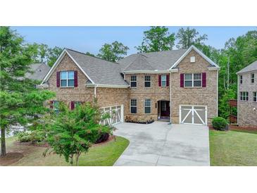 Lovely two-story brick home with well-manicured lawn and a spacious three-car garage and inviting burgundy shutters at 4395 Wildbrooke Pkwy, Cumming, GA 30041