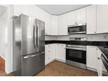 Bright kitchen features white cabinets, stainless steel appliances, and dark countertops at 1211 Argonne Ne Way, Atlanta, GA 30324