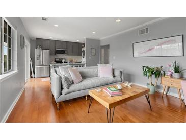 Bright living room featuring hardwood floors, gray walls, a comfortable gray sofa, and a view to the kitchen at 1705 Monroe Ne Dr # D01, Atlanta, GA 30324