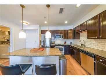 Modern kitchen with granite countertops, stainless steel appliances and a kitchen island with bar stool seating at 200 River Vista Dr # 236, Atlanta, GA 30339