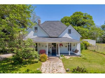 Charming two-story home featuring a welcoming front porch with swing, stone pathway, and well-maintained lawn at 215 Fair St, Loganville, GA 30052
