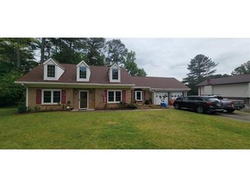 Charming brick home with a well-manicured lawn, dormer windows, and a two-car garage at 4662 Burns Rd, Lilburn, GA 30047