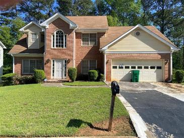 Charming two-story brick home featuring an attached two-car garage and well-maintained front lawn at 5001 Panola Mill Dr, Lithonia, GA 30038